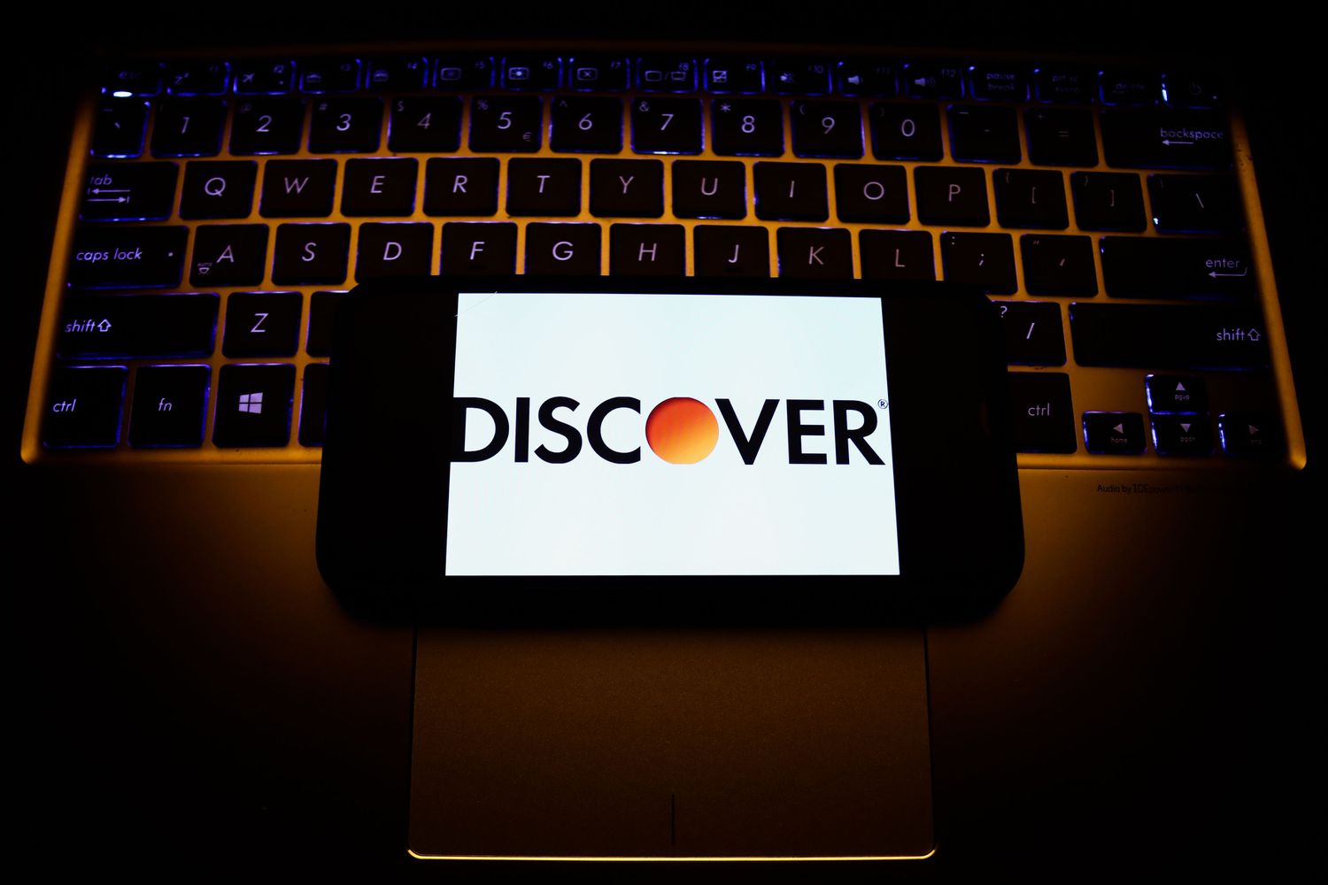 Discover logo displayed on a smartphone screen lying on a laptop keyboard