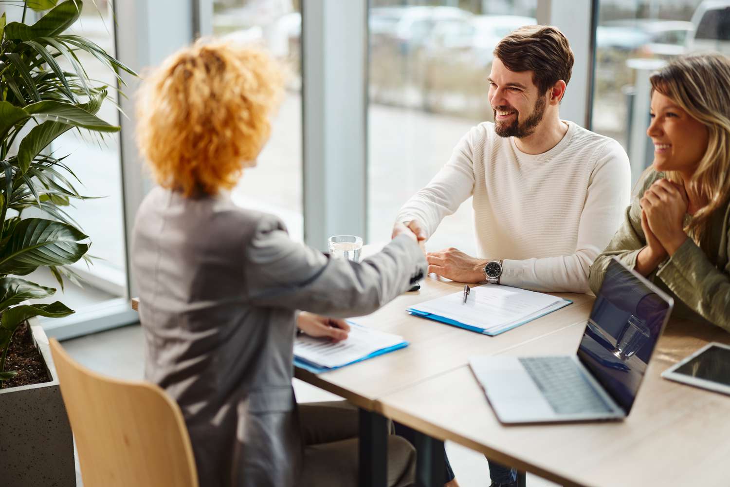 Happy couple shaking hands after reaching a successful deal from a primary lender of primary mortgage market.