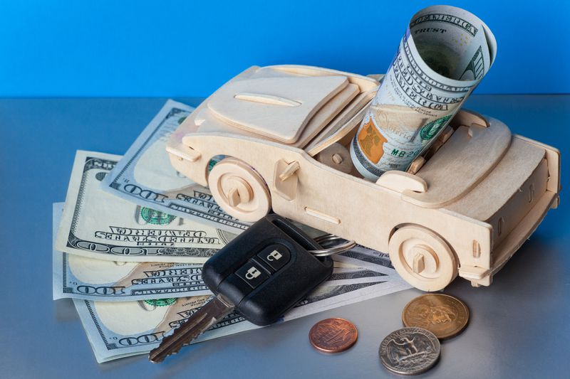 A toy convertible with car keys and hundred dollar bills