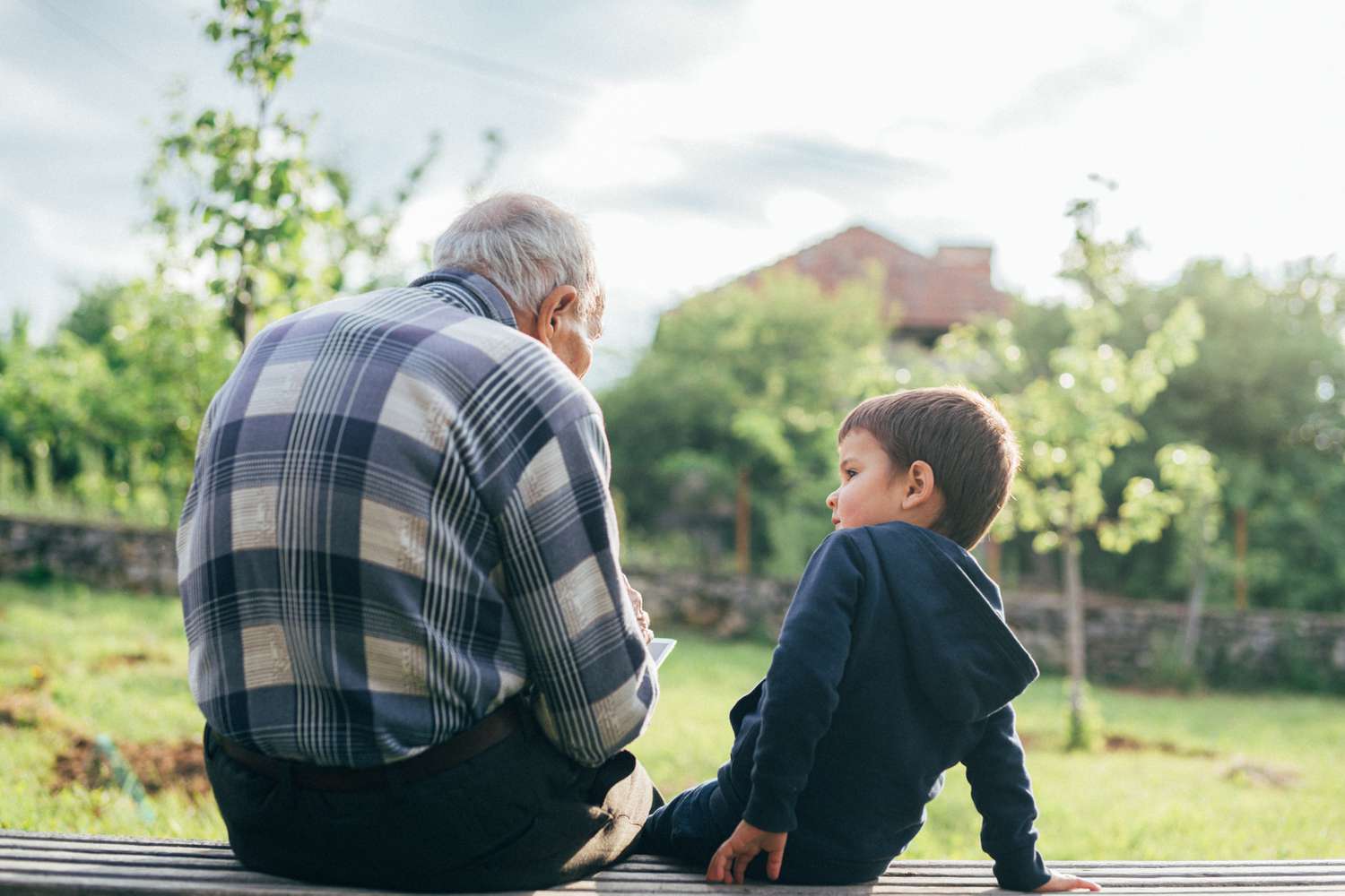 An older adult and a child sit on a bench 
