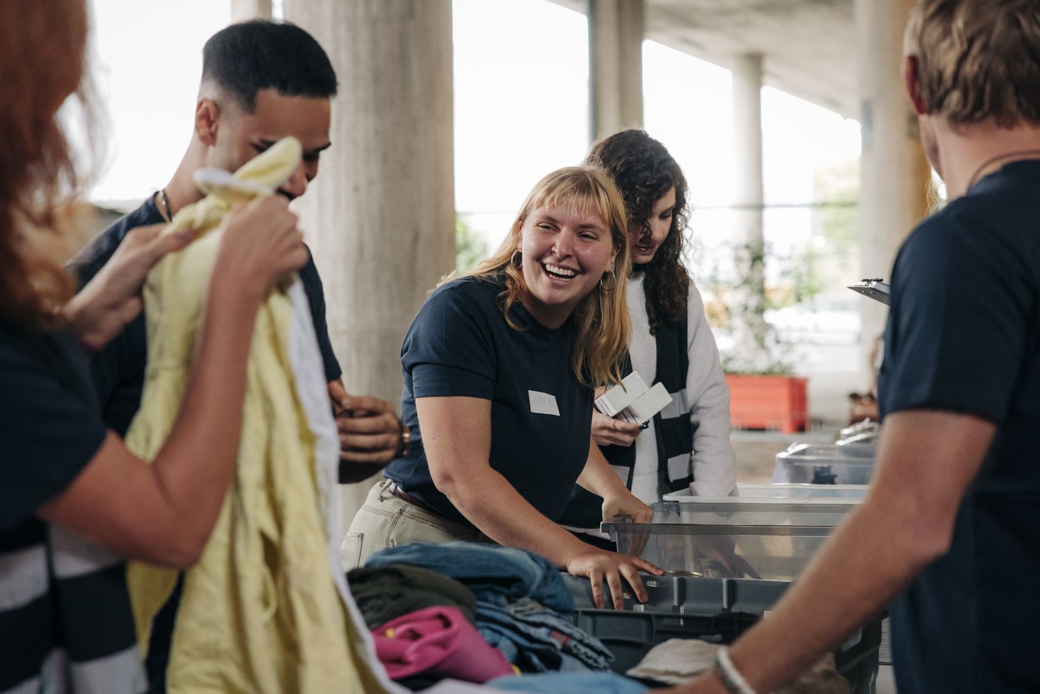 Volunteer laughing with another volunteer while they sort clothes and prep for a clothes drive.