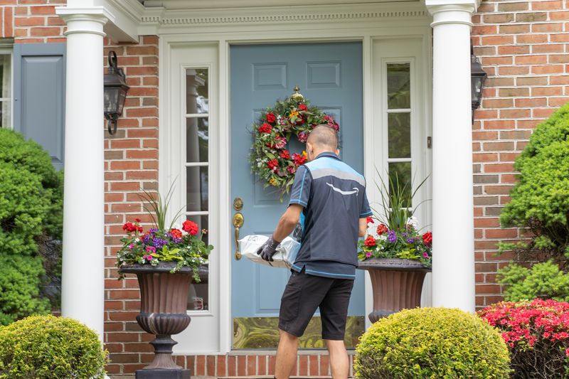 Amazon.com delivery person delivers a package to a front door