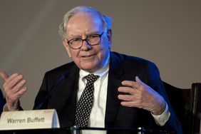 Warren Buffett gestures with his hands while speaking at a panel event