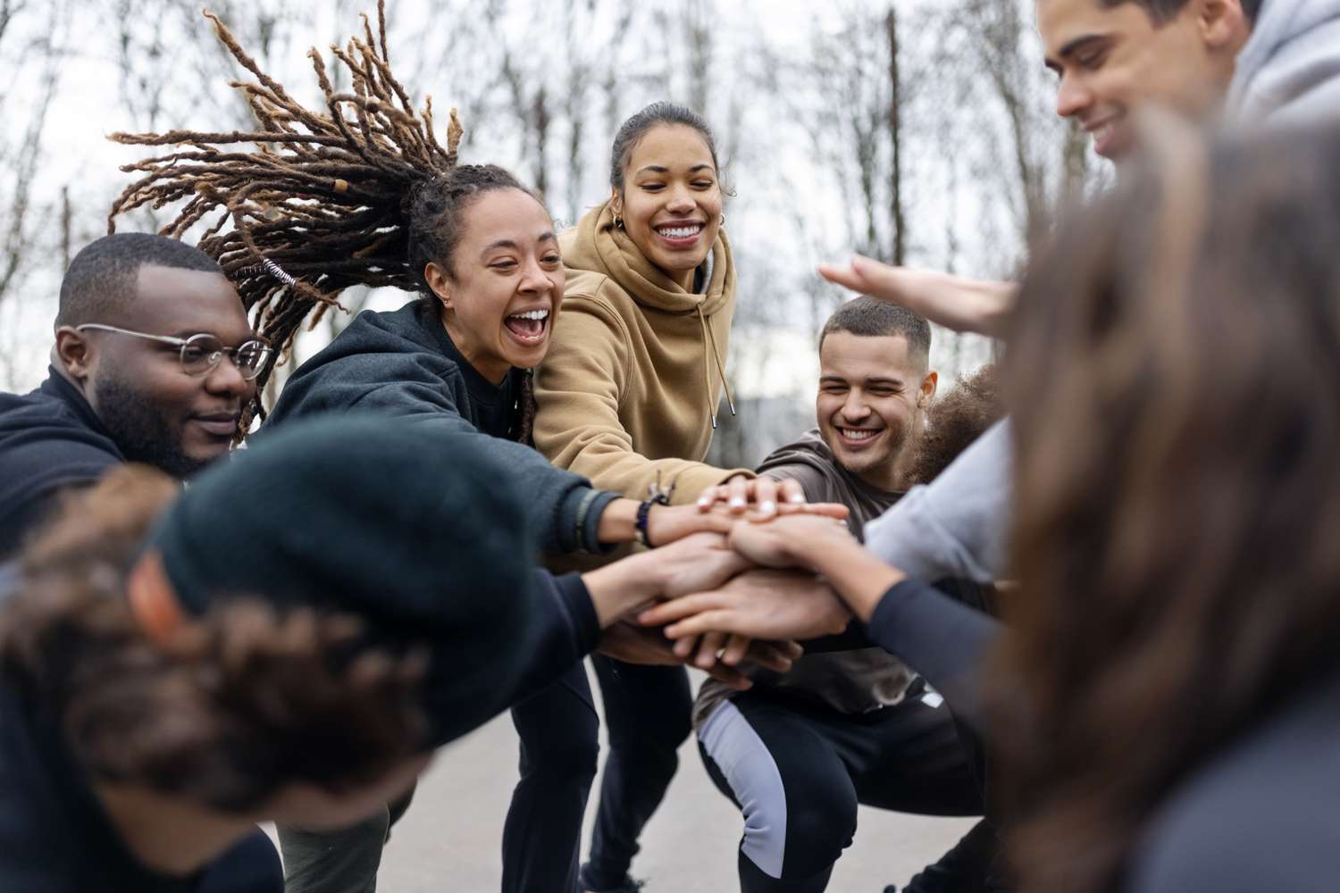 People stacking hands while playing a game outdoors