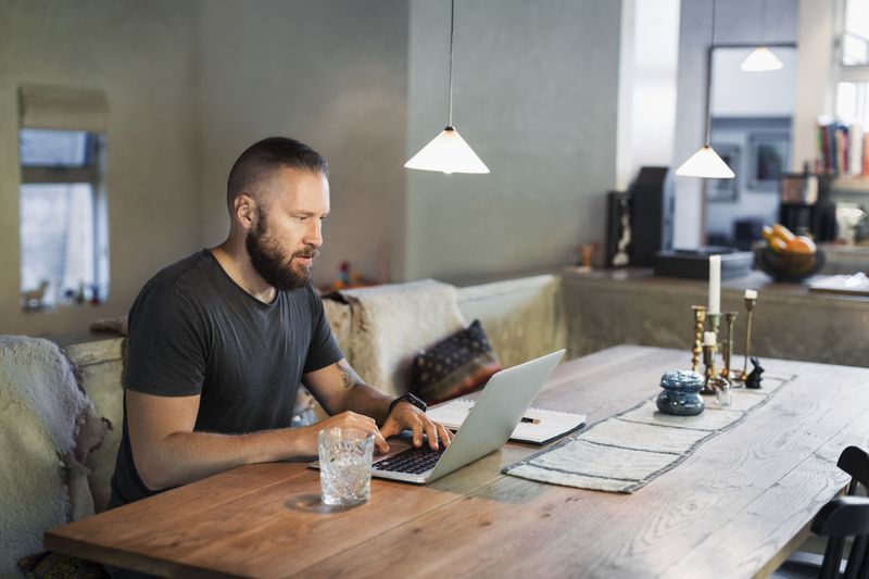 A man works on a laptop in a home.
