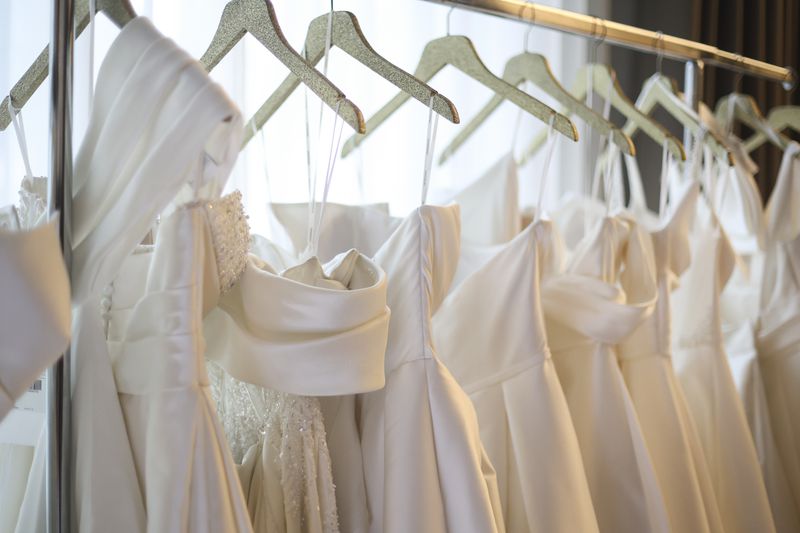 A rack of wedding dresses on hangers in a shop. 