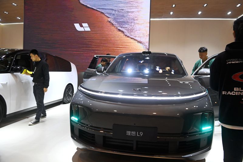 People are seen standing around two electric vehicle on the floor of an auto show.