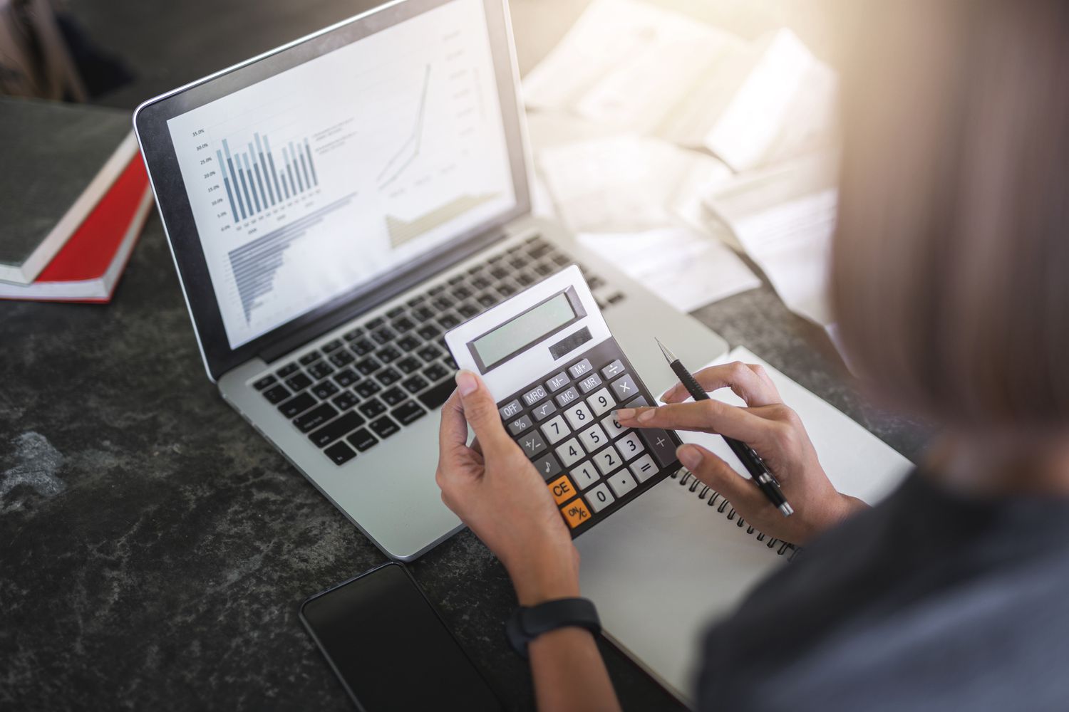 a woman using a calculator in front of a laptop