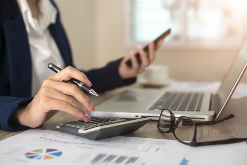 Close up of female accountant or banker making calculations. Savings, finances and economy concept
