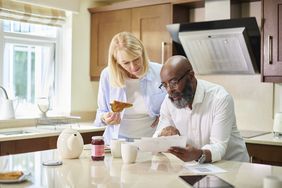 Older couple looks over paperwork in their kitchen