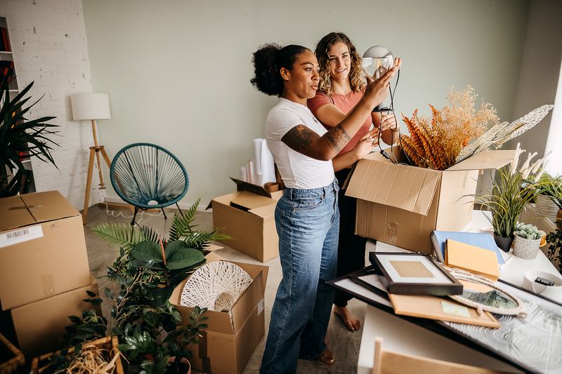 Two women unpack moving boxes in their new apartment. 