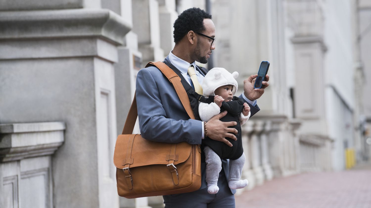 Man with infant checking cell phone