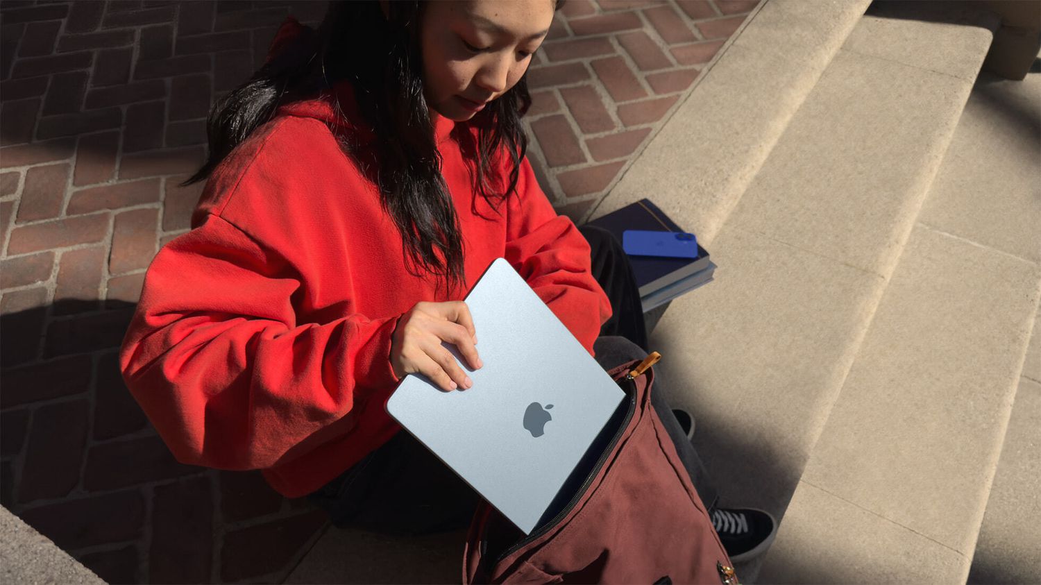 A woman stashes an Apple MacBook in her bag. 