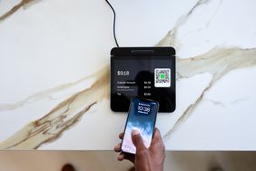 Cropped hand of customer tapping smartphone on point-of-sale (POS) system in coffee shop