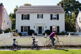 A family bikes in front of a home.