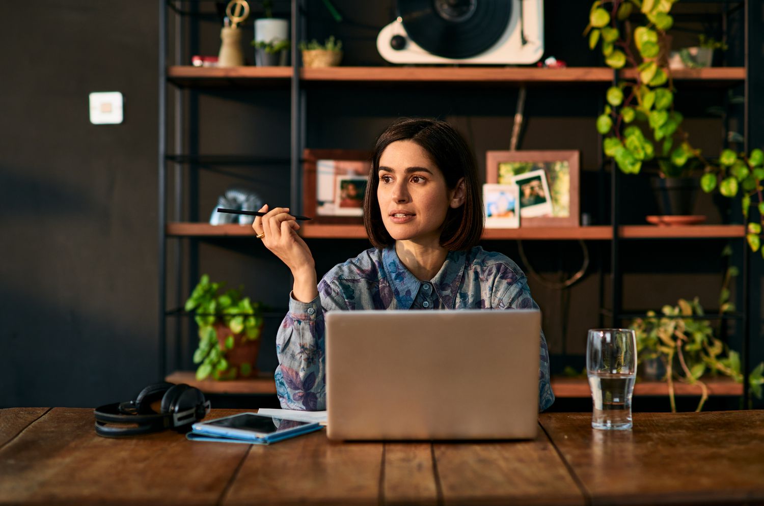 Woman in an office sitting at a table with a laptop and a glass of water. 