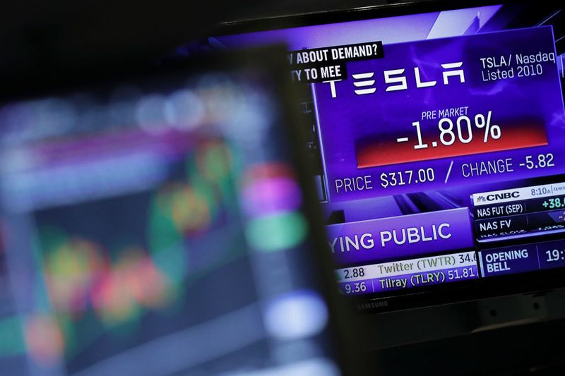 The Tesla logo is displayed on a television broadcast on the floor of the New York Stock Exchange.
