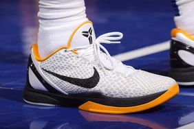 A white, black, and yellow Nike shoe is seen on a basketball court.