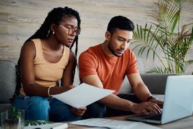 A couple reviews paperwork and works on a laptop.