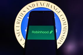 The green Robinhood logo is seen on a phone screen in front of the Securities and Exchange Commission seal in the background.