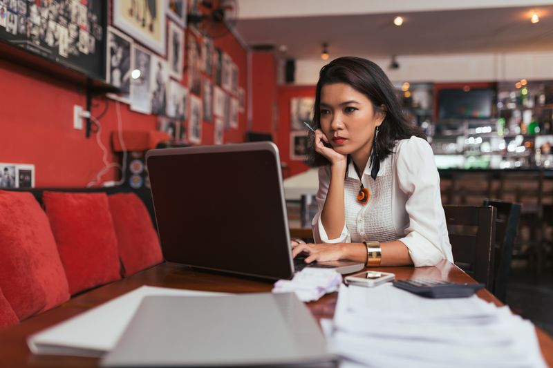 A woman on a laptop surrounded by papers
