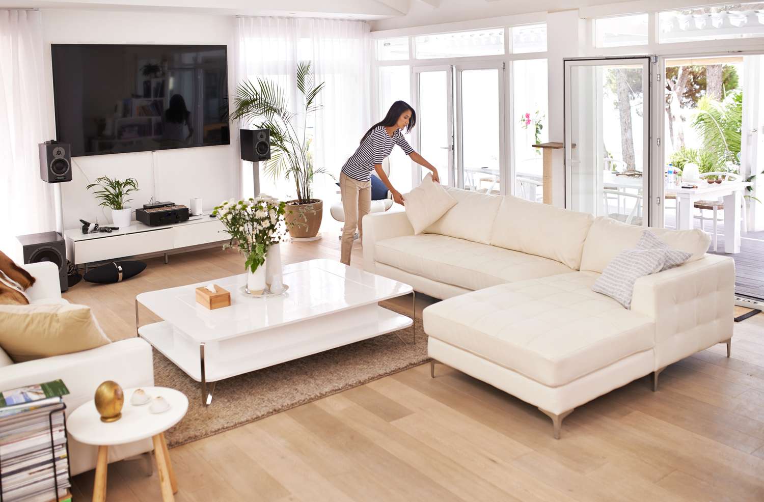 A woman arranges furniture in a living room.