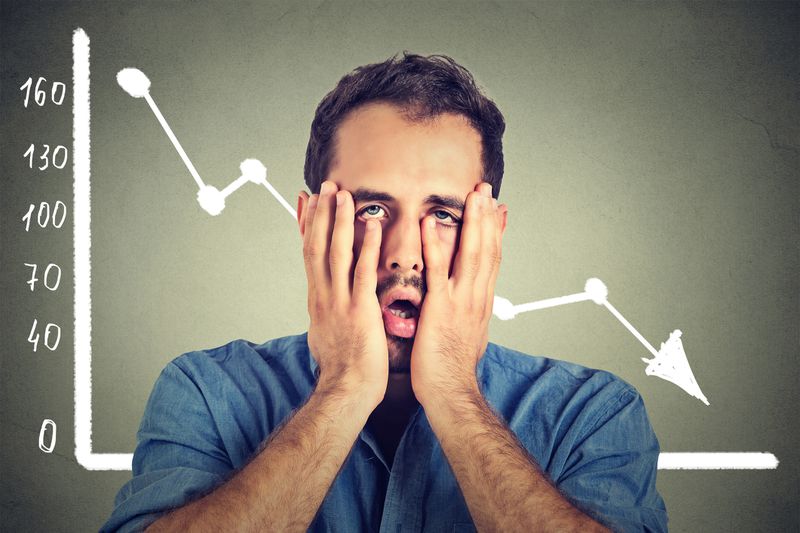 Stressed man desperate with financial market graphic going down.