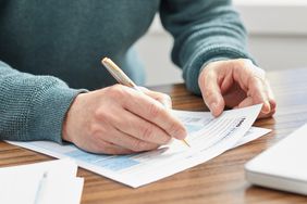 Person holding a pen and filling out a tax form