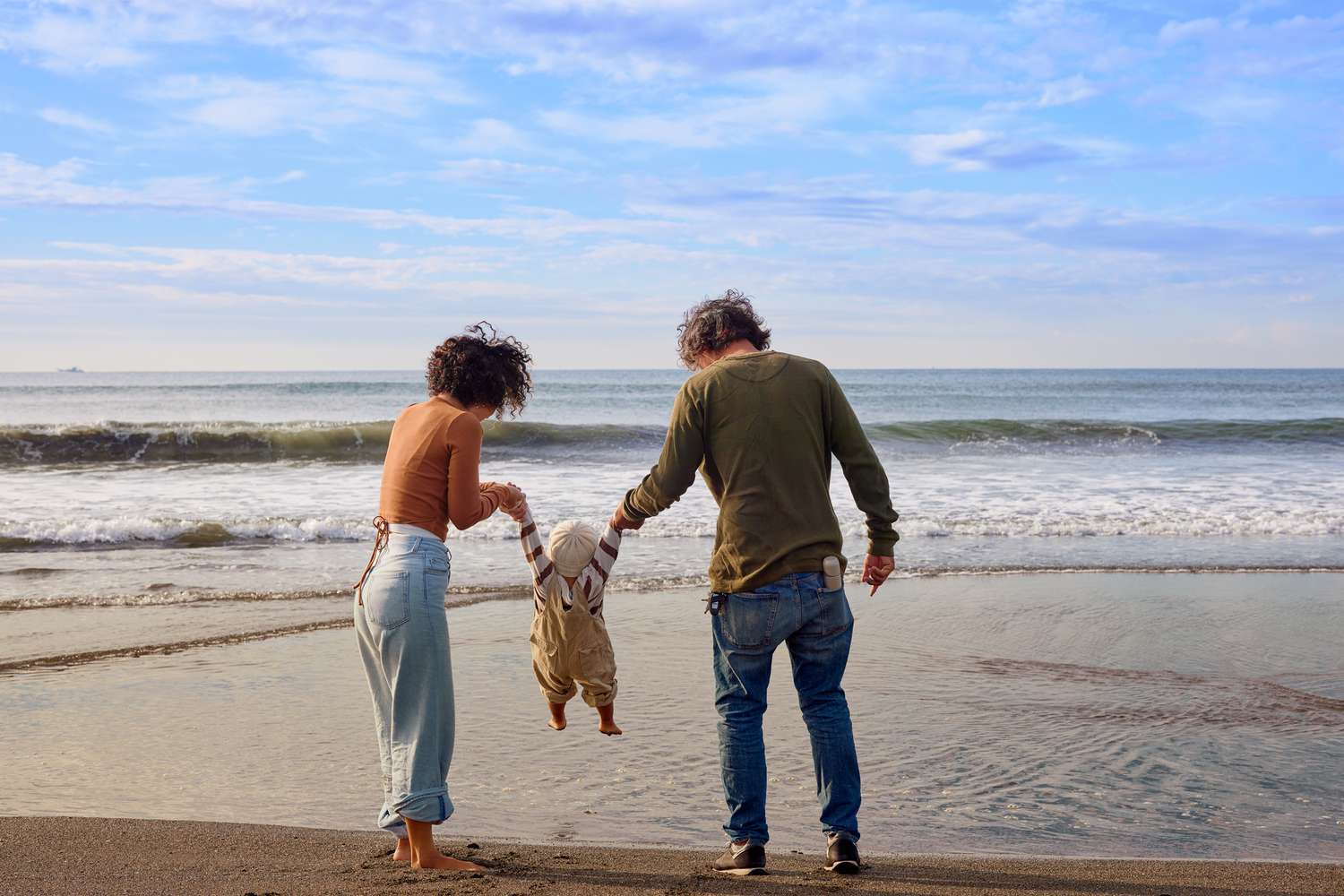 Young couple on beach with baby.