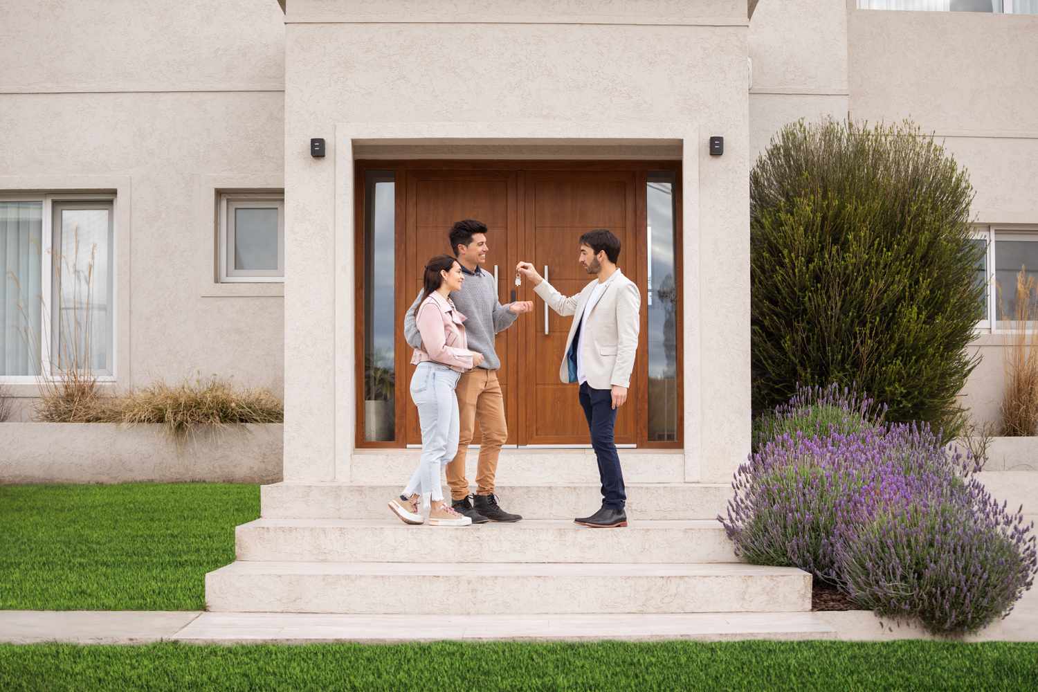 Happy couple receiving key to their new home from the realtor after winning the bidding war with an all-cash offer.