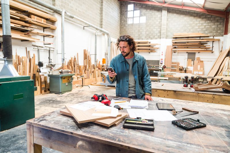 a man in a wood workshop looking at his phone