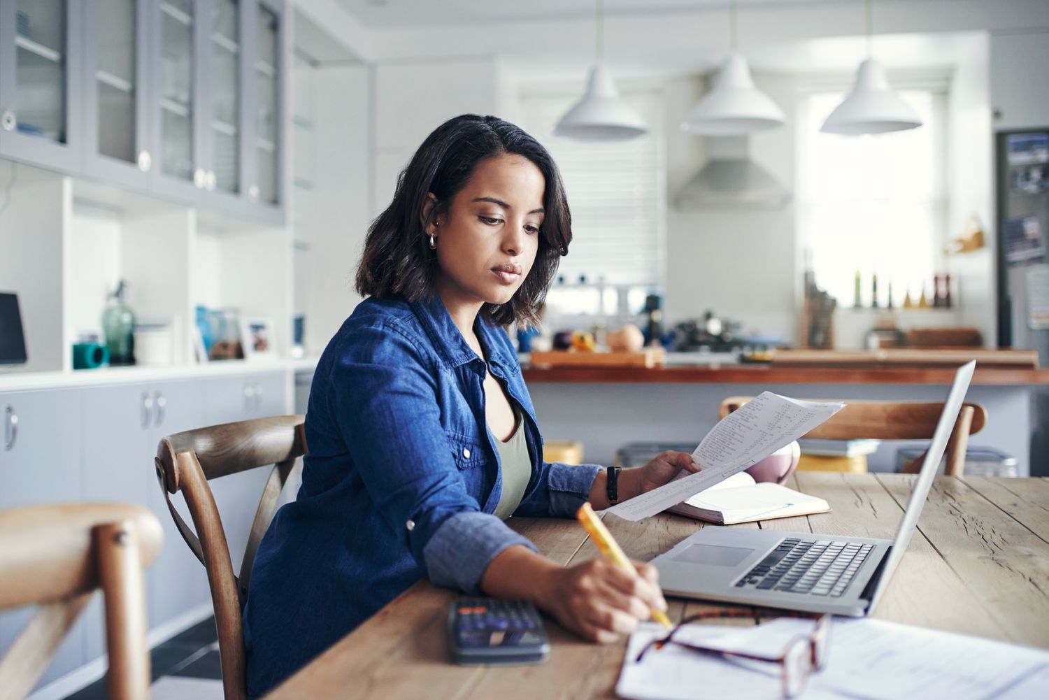 A woman completes paperwork at a desk.