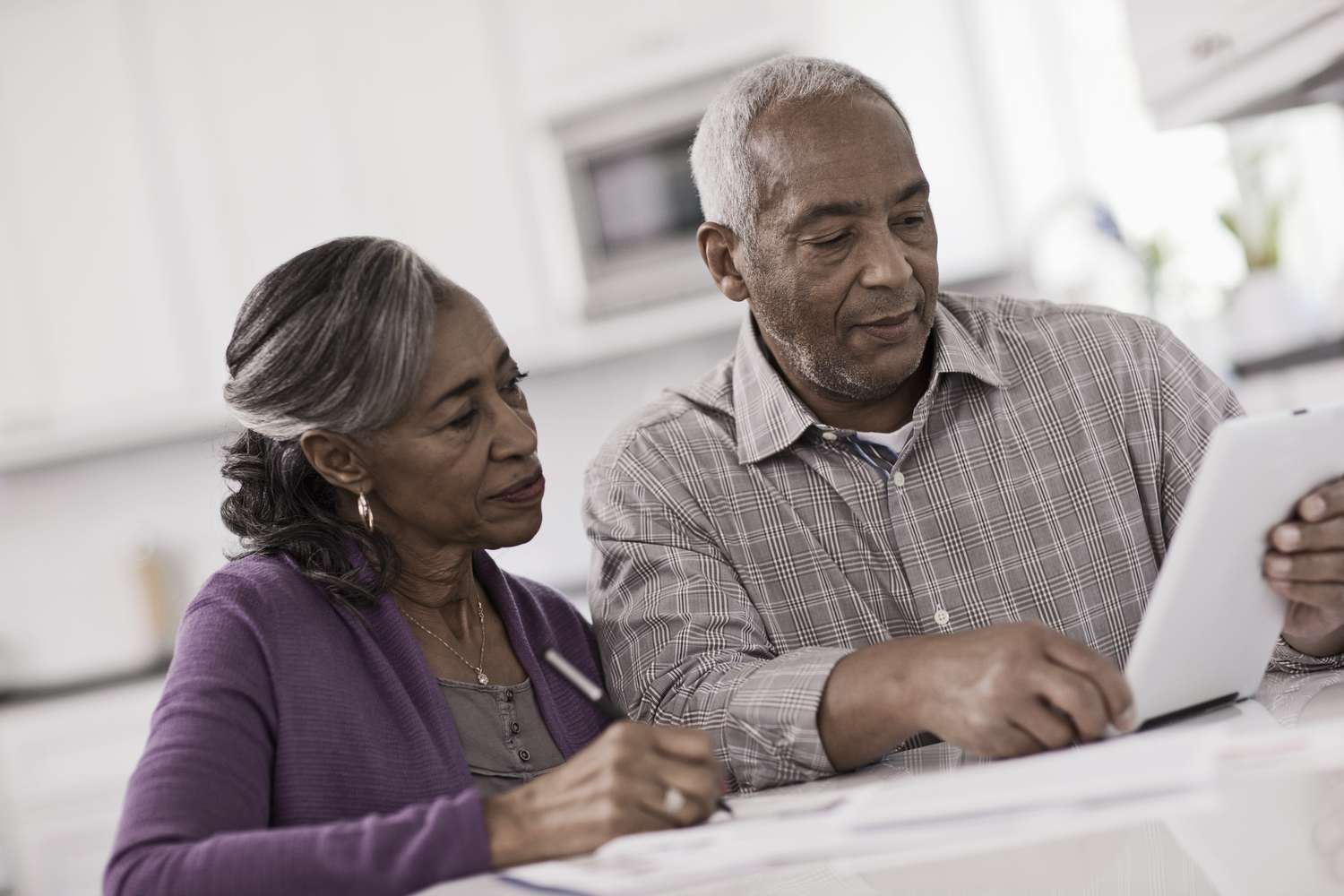 Older couple sitting in their kitchen and looking at mortgage rates on their tablet