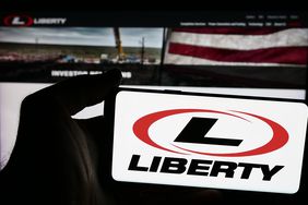 A person is holding a smartphone with the logo of US oilfield services company Liberty Energy Inc. in front of website