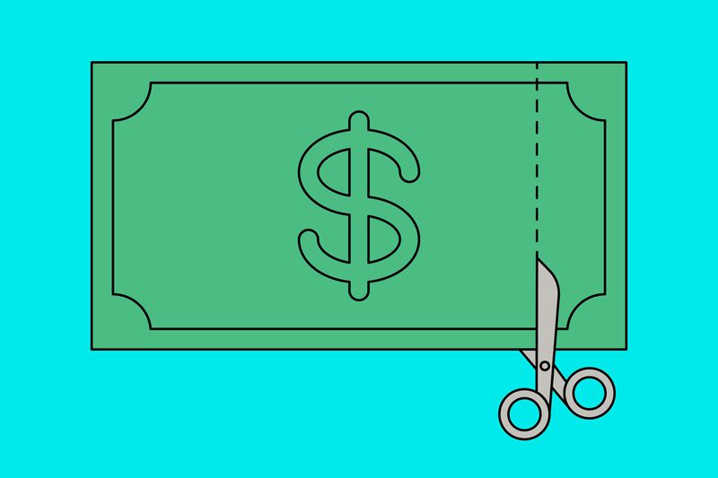 Illustration of scissors cutting a dollar bill. 