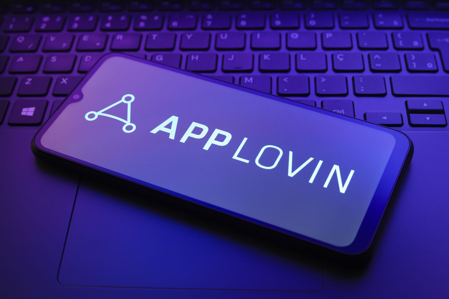 Applovin logo on a smartphone screen resting on a laptop keyboard