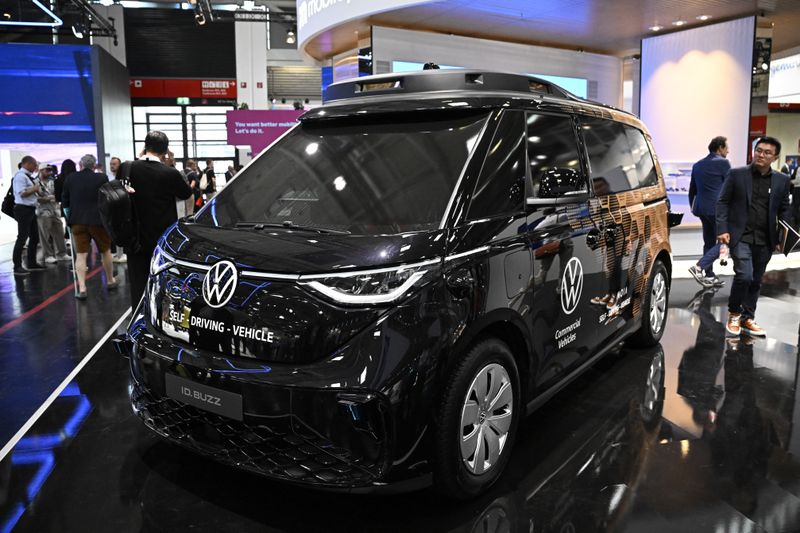 A Volkswagen autonomous concept van displayed at an exhibition with people in the background