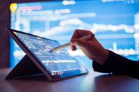 Woman using a tablet with a tablet pen showing stock market data