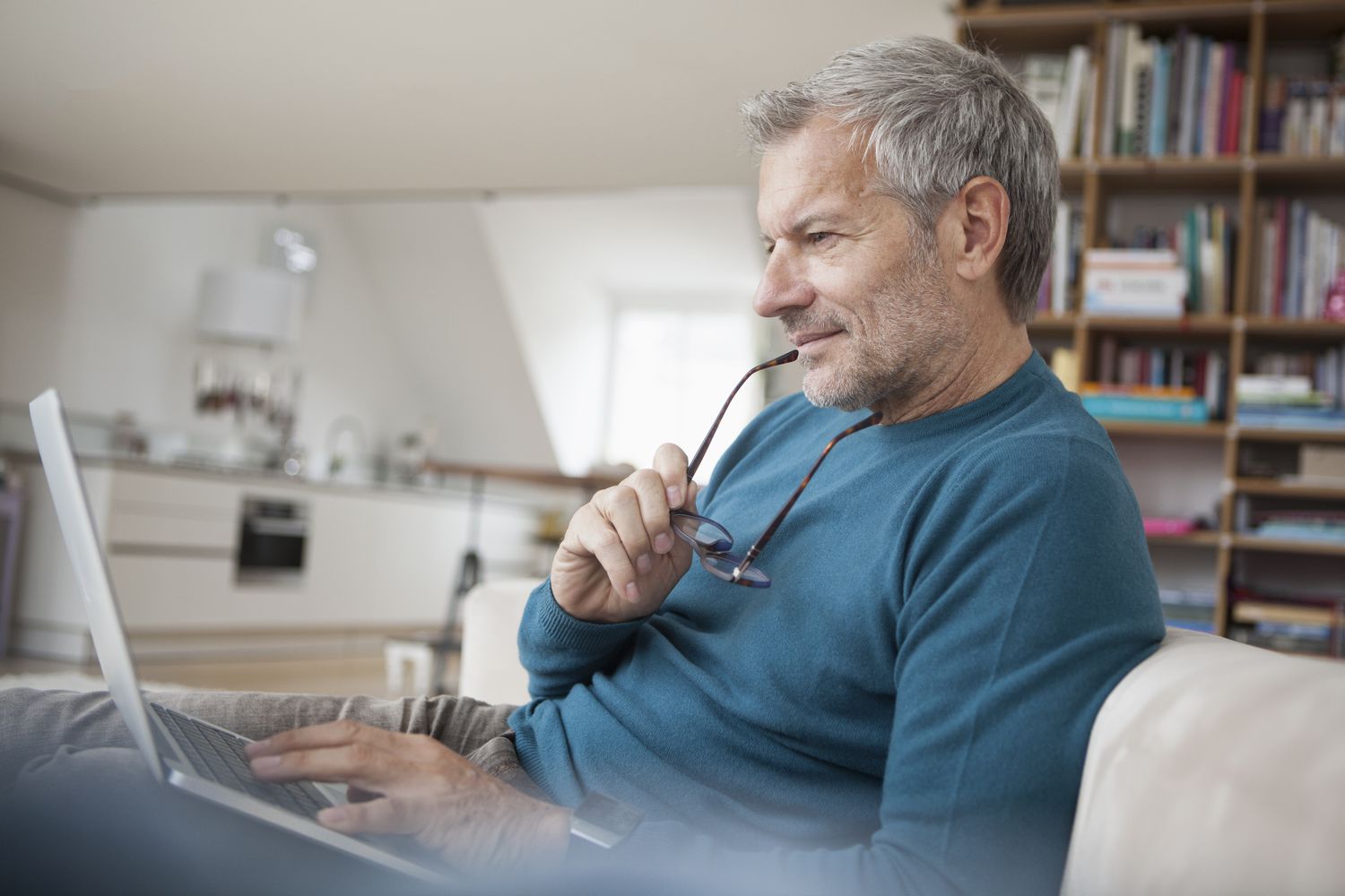 Older man at home intently studying something on his laptop