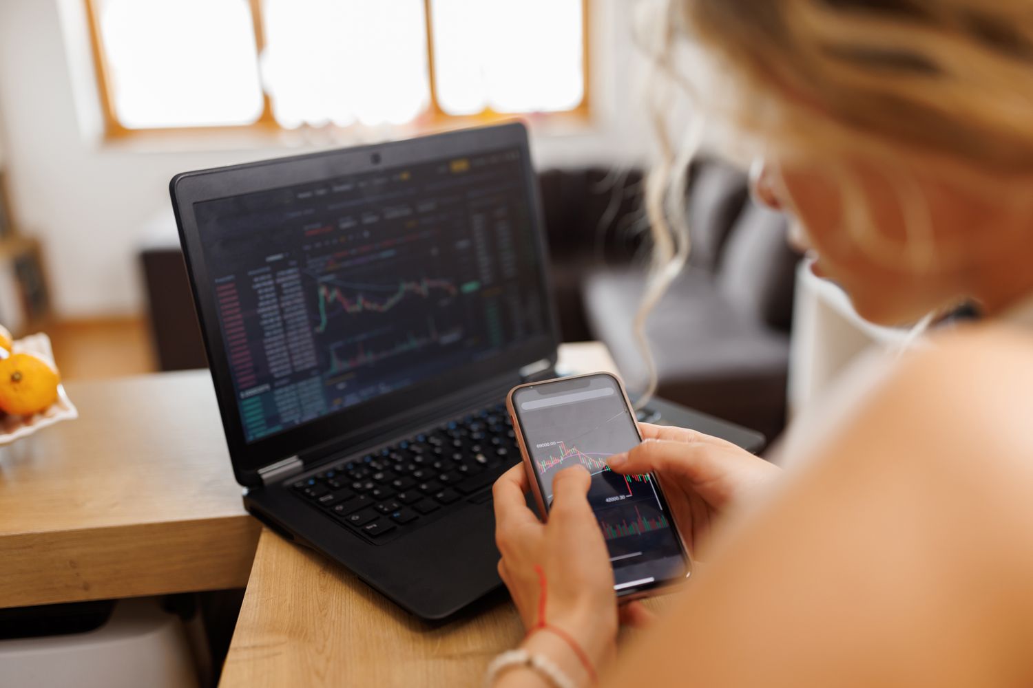 Woman looking at a mobile device and an open laptop