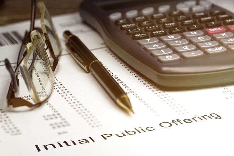 IPO (Initial public offering) wording with calculator, ballpoint pen and pair of reading glasses.