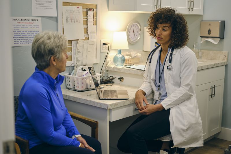 Female doctor talks to older female patient in an exam room