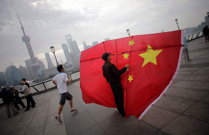 A man running next to another man holding up a Chinese flag.
