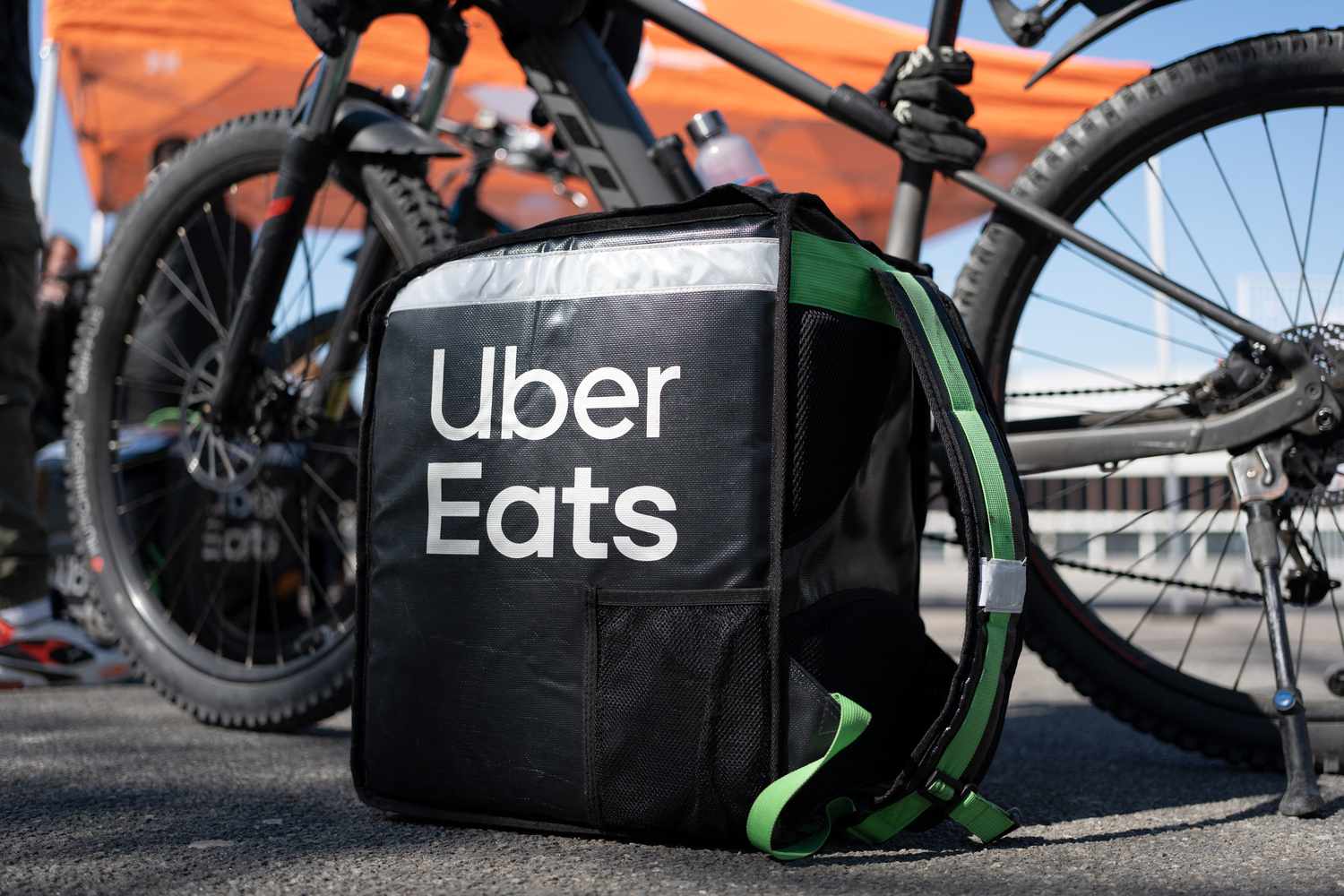 An Uber Eats delivery bag sits on the ground in front of a black bicycle