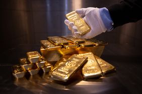 Gold bars and a gloved hand holding one bar.