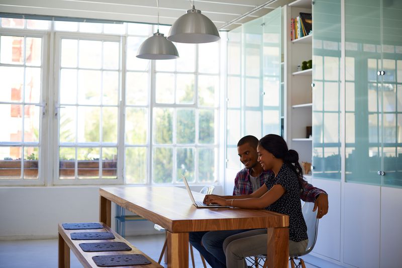 Young couple looking at laptop in bright kitchen.