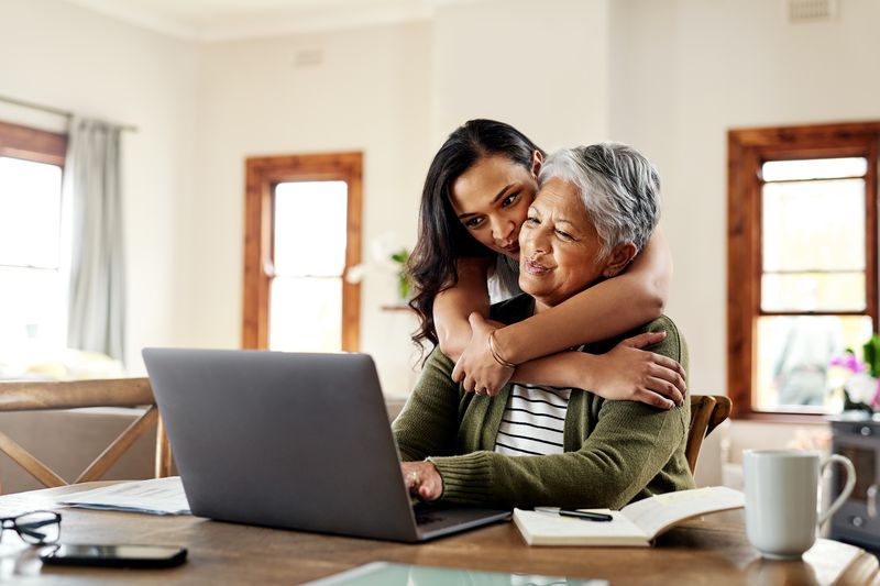 Cropped shot of a young person hugging her grandmother before helping her with her finances on a laptop