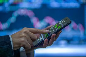 A businessperson using a mobile phone to check stock market data.