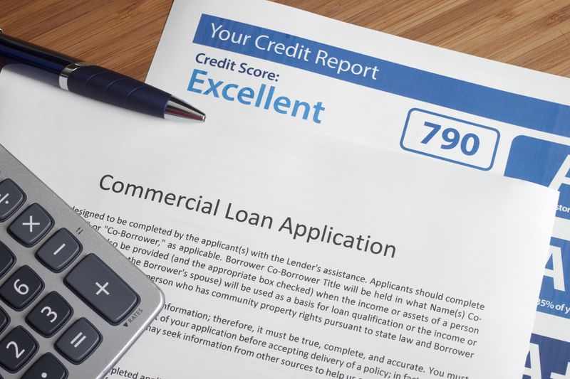 A consumer credit report with excellent score on the table next to a loan application.