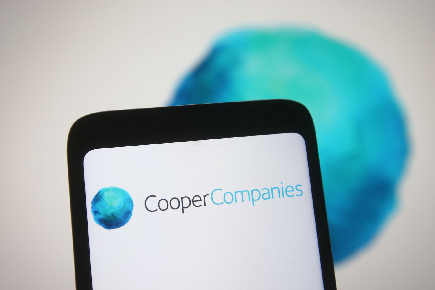 Cooper Companies logo is seen on a smartphone and a PC screen